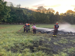 Firefighters from Chartiers Township Volunteer Fire Department use a fire hose to extinguish a fire in a field.